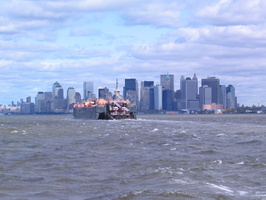Un bateau pousseur remorque une barge devant Manhattan